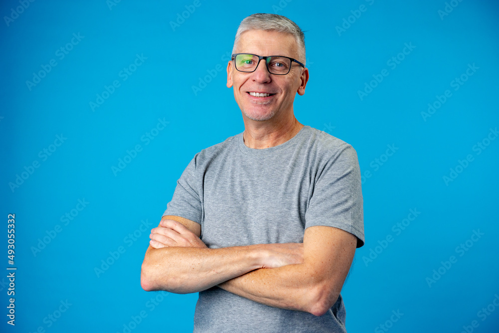 Portrait of senior man with arms crossed over blue background Portrait of senior man with arms crossed over blue background