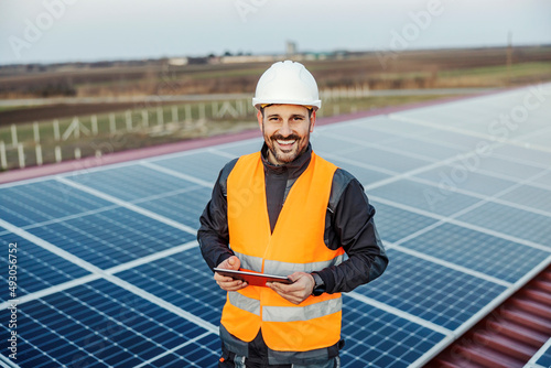 A handyman holding tablet for checking on solar panels and smiling at the camera. photo