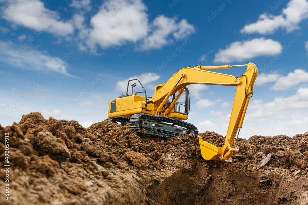 Excavator with bucket lift up are digging soil in the construction site on the cloud and sky background Excavator with bucket lift up are digging soil in the construction site on the cloud and sky background