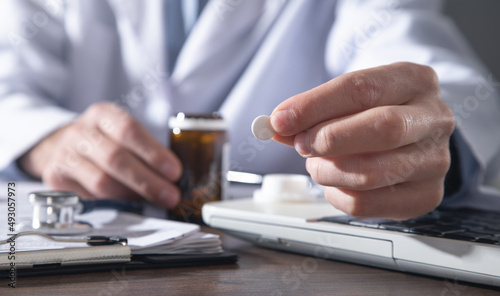 Caucasian doctor holding pill in clinic.