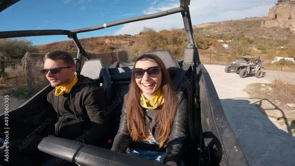 Young couple driving a buggy UTV ATV Can-am polaris on desert off-road in Ronda, Spain, on a sunny day . Couple having fun riding a ATV off-road