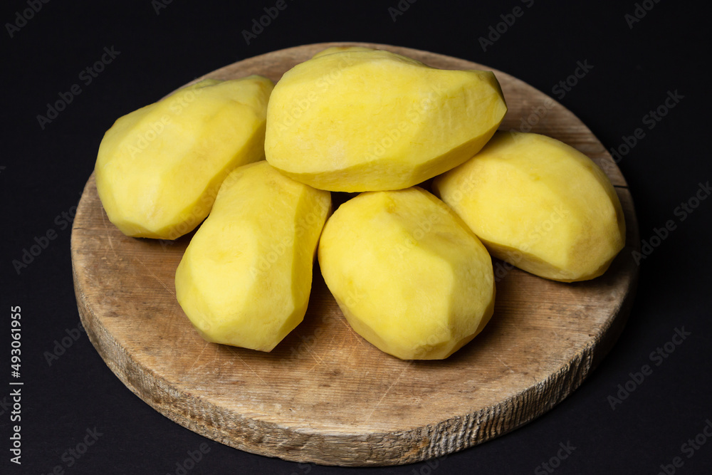 Peeled potatoes on a black background. Delicious and healthy vegetable. food preparation ingredient