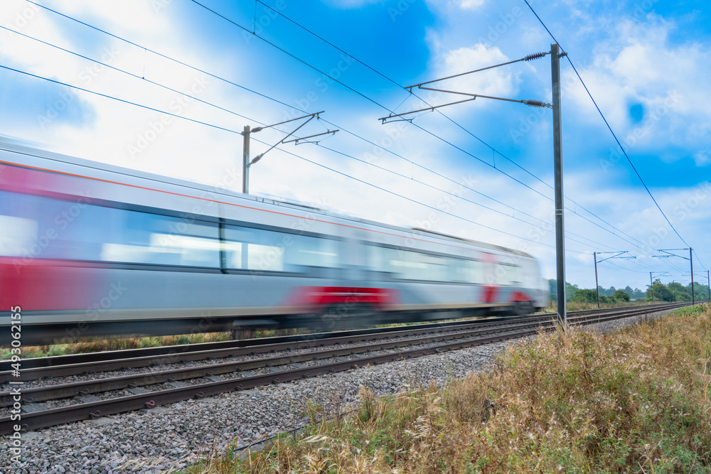 Close up of a train with overhead electrification speeding through English countryside with motion blur
