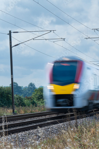 Close up of an express train with overhead electrification speeding through English countryside with motion blur