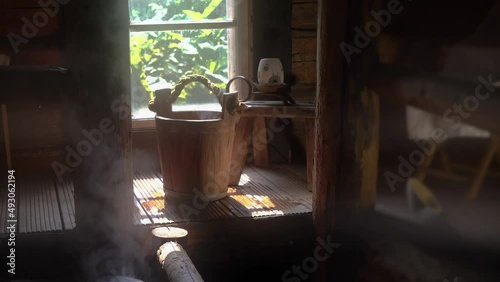 Interior of traditional Finnish sauna with wooden accessories and steam. Splashing water on hot stones. photo