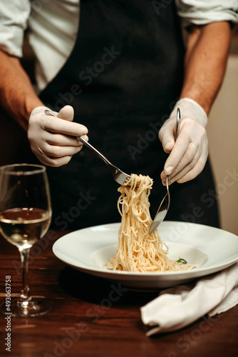 The chef in the restaurant shows how to eat spaghetti