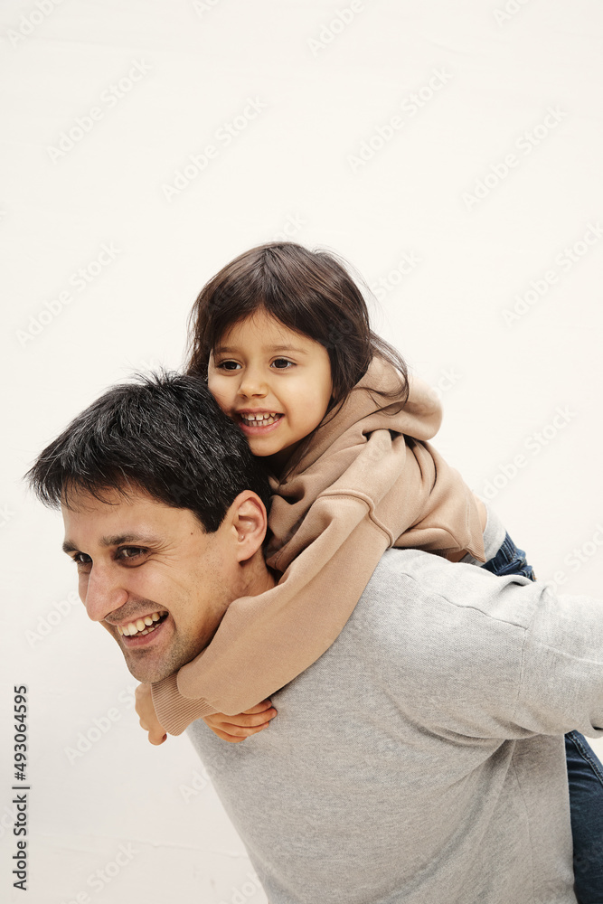 Portrait of excited little girl sitting on her back, young father playing together at home, happy loving dad feeling playful, continuing happy little daughter, family weekend concept Portrait of excited little girl sitting on her back, young father playing together at home, happy loving dad feeling playful, continuing happy little daughter, family weekend concept