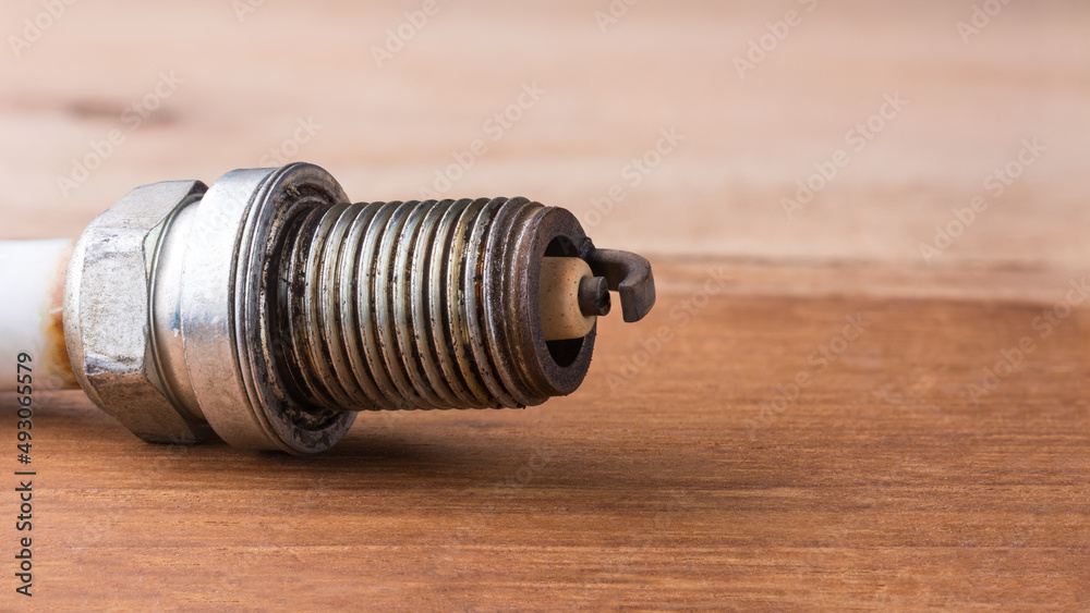 used worn spark plug in shallow depth of field on a table top, closeup macro with copy space
