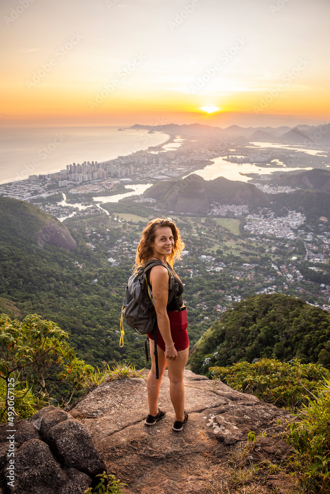 Beautiful sunset view to woman on rocky rainforest mountain