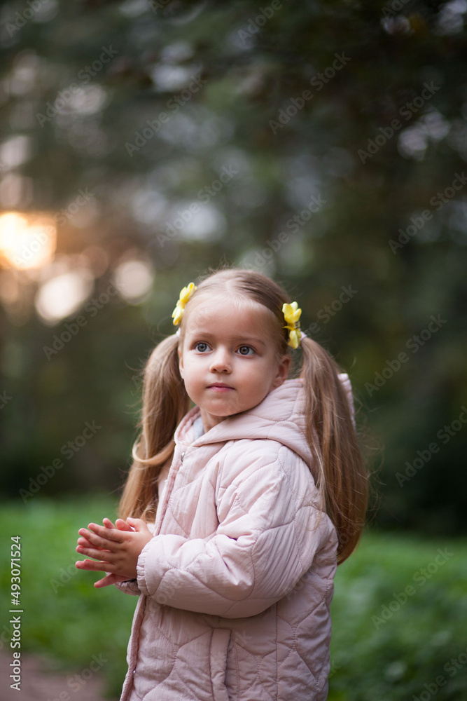 Small blonde european girl portrait with pig-tails with flowers in evening, outdoors, in forest. Big eyes and smart smile Small blonde european girl portrait with pig-tails with flowers in evening, outdoors, in forest. Big eyes and smart smile