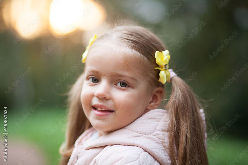 Small blonde european girl portrait with pig-tails with flowers in evening, outdoors, in forest. Big eyes and smart smile Small blonde european girl portrait with pig-tails with flowers in evening, outdoors, in forest. Big eyes and smart smile