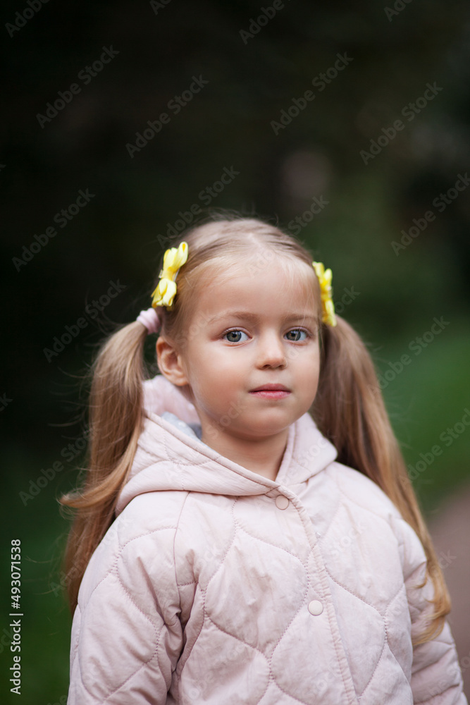 Small blonde european girl portrait with pig-tails with flowers in evening, outdoors, in forest. Big eyes and smart smile Small blonde european girl portrait with pig-tails with flowers in evening, outdoors, in forest. Big eyes and smart smile