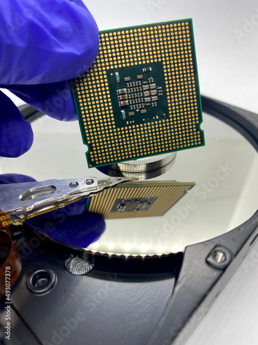 Gloved hand keeping a microprocessor against a hard disk with reflections closeup view