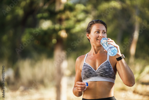 Woman Runner Is Drinking Water And Preparing To Jogging In Park At Summer Day
