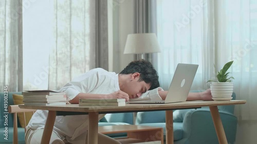 Asian Man Student Sleeping While Using Computer To Study Online At Home
