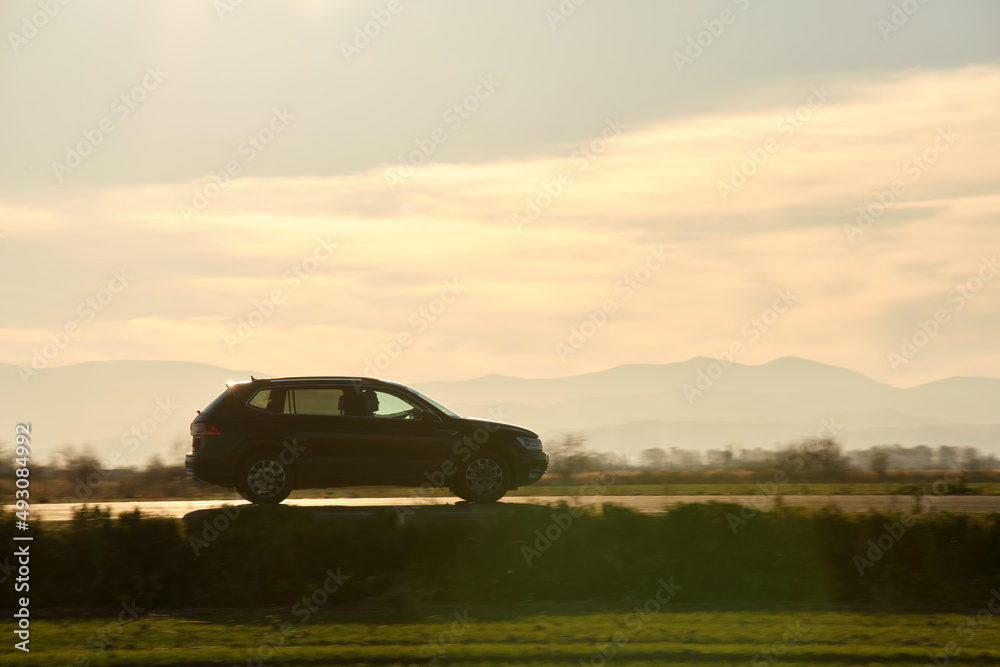 Fototapeta premium Car driving fast on intercity road at sunset. Highway traffic in evening