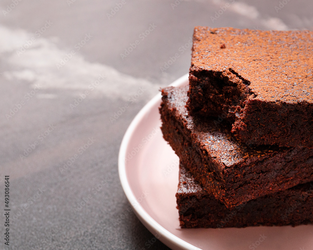 Slices of brownie dessert on a dark background on a pink plate
