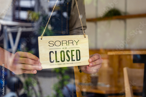 A coffee shop owner flips the sign off the shop several hours after it's been open, cafe owner concept.