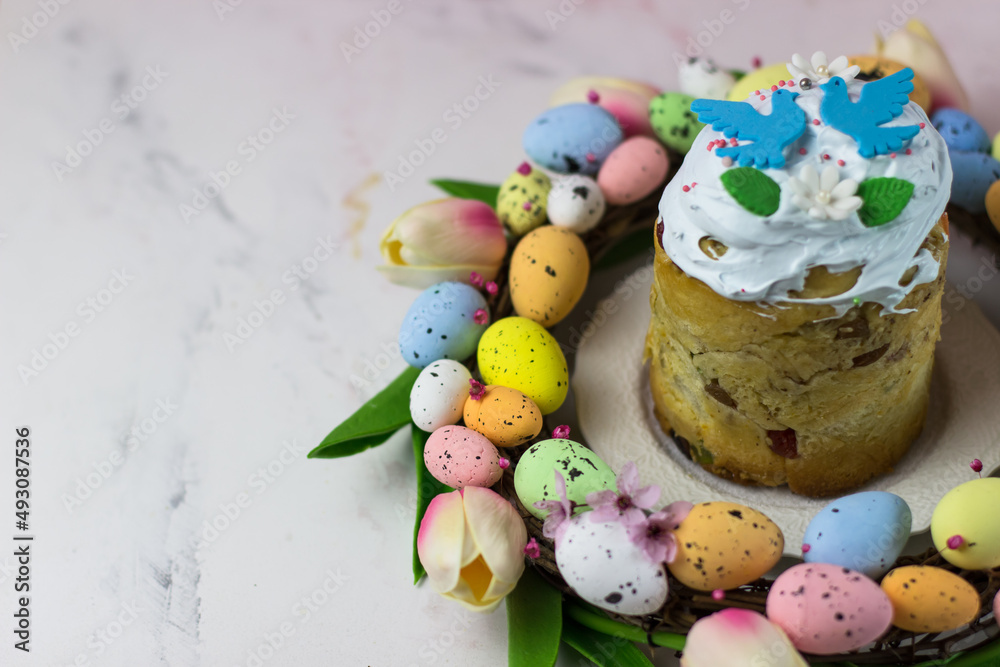 Easter card. Kulich with sugar fudge in a wreath of tulips and eggs. Marshmallow fudge with decoration. Place for text