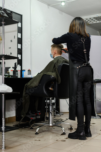 Hairdresser puts hair to teen boy after haircut, haircut for teen.