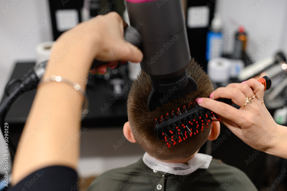The hairdresser dries and styles the hair with the help of a hair dryer