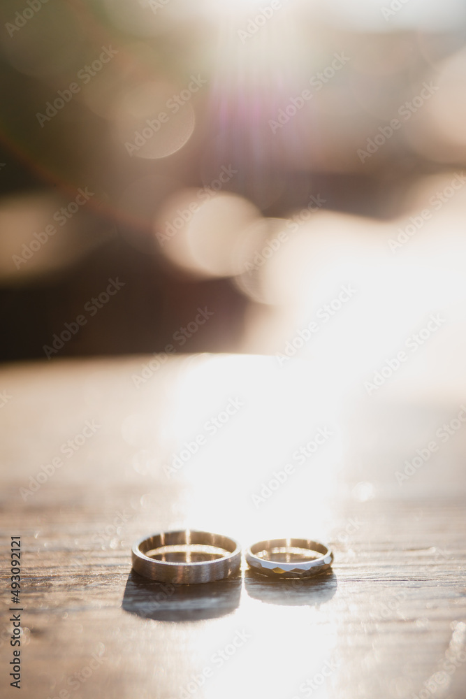Modern wedding jewelry. Closeup of two golden wedding rings on wooden background.