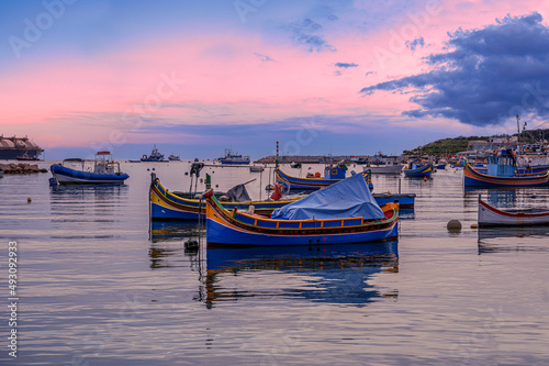 Traditional Maltese boats in Marsaxlokk harbor during sunset, Malta photo