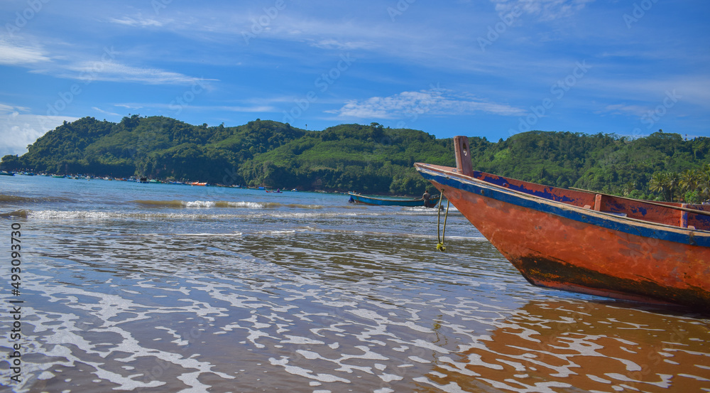 Traditional wooden fishing boats and beautiful hilly beach in East Java province, Indonesia.
boat background on the beach, beautiful Indonesian beaches. beach background.