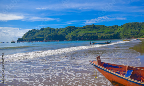 Fototapeta Naklejka Na Ścianę i Meble -  Traditional wooden fishing boats and beautiful hilly beach in East Java province, Indonesia.
boat background on the beach, beautiful Indonesian beaches. beach background.