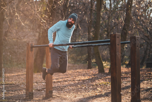 Man enjoys exercise push- ups on parallel bars in the park.