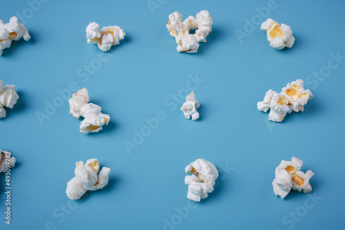 Popcorn lay out on blue background, close up shot. Food pattern