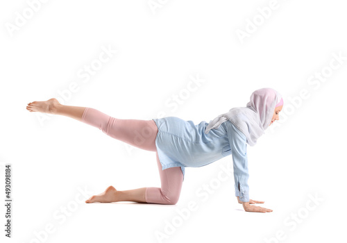Pregnant Muslim woman doing yoga on white background