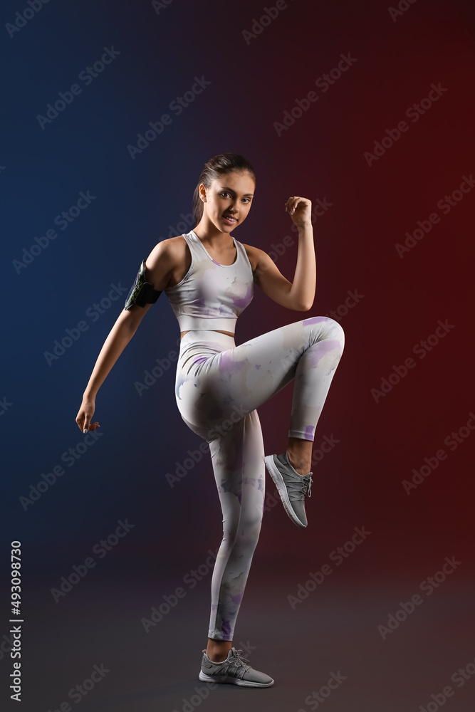 Sporty teenage girl with armband training on dark background