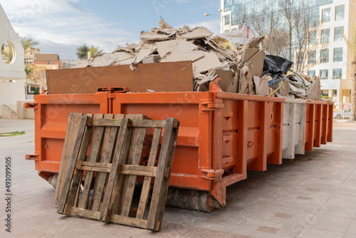 huge heap on metal Big  Overloaded dumpster waste container filled with construction waste, drywall and other rubble near a construction site. photo