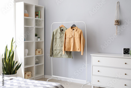 Rack with stylish jackets near light wall in bedroom © Pixel-Shot