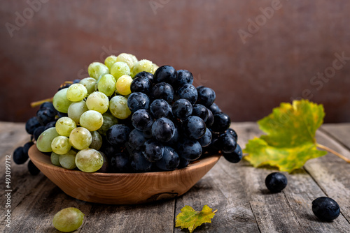 Bowl with grapes on wooden background