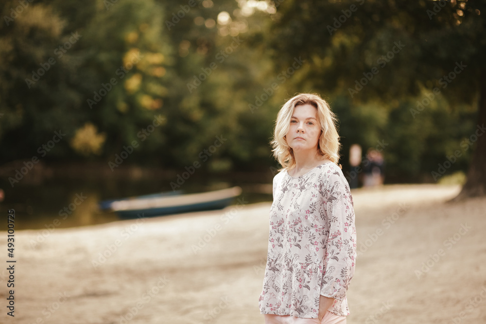 Naklejka premium Young woman stands on the bank of the river and looks at the camera