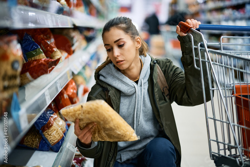 Young woman buying pasta in supermarket. photo
