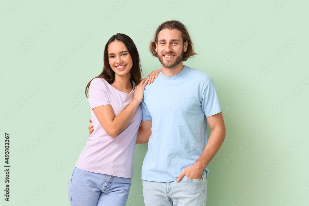 Young couple in stylish t-shirts on green background Young couple in stylish t-shirts on green background