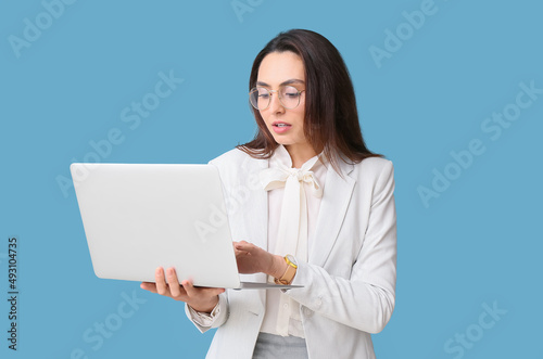 Portrait of young secretary with laptop on blue background