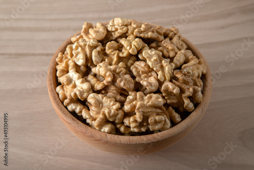 Bowl full of peeled walnuts on a wooden background,top view	