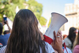Woman seen from the back holding a megaphone during the feminist strike