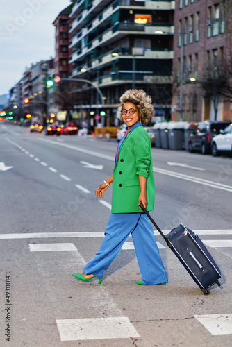Portrait of attractive positive curly hairstyle dark skin lady with a suitcase for luggage