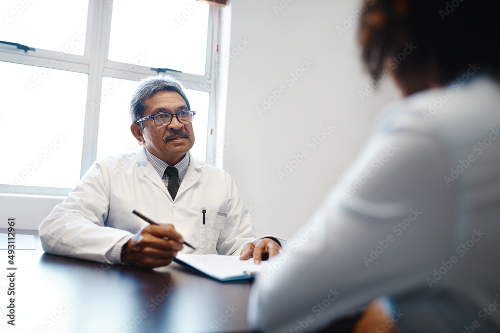 Tell me more about your symptoms.... Shot of a mature doctor having a consultation with a patient in his office. Tell me more about your symptoms.... Shot of a mature doctor having a consultation with a patient in his office.