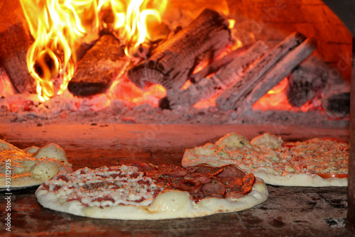 Três pizzas sendo assadas em ume um forno a lenha photo