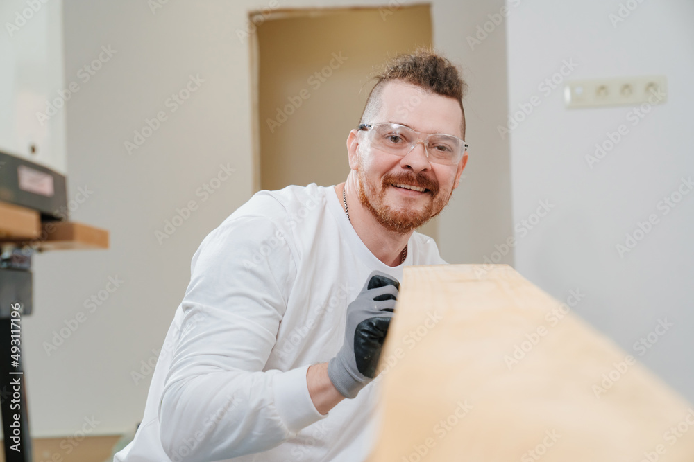 carpenter in protective gloves and glasses with wood