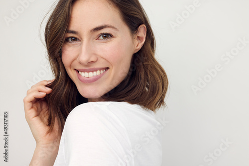 Portrait of beautiful naturally brunette woman, smiling and looking in camera with white teeth. Close-up portrait of cute female girl isolated on white background. 