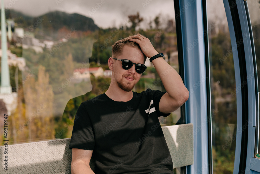 Stylish handsome man in sunlight is touching his hair and posing at camera while traveling around the city. Travel concept. man travel in Europe Stylish handsome man in sunlight is touching his hair and posing at camera while traveling around the city. Travel concept. man travel in Europe