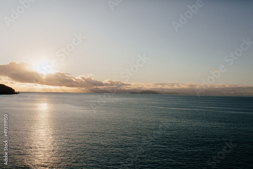 Picture of blue blue calm ocean at sunset. Landscape of ocean with low clouds and sun © PhotoBook