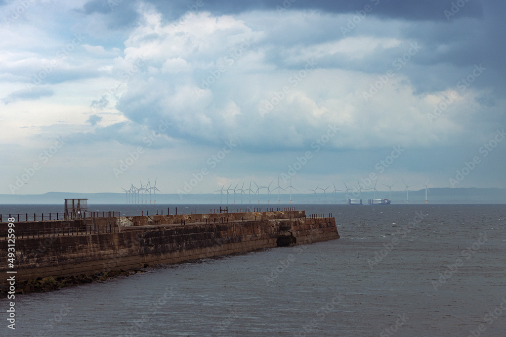 Heugh breakwater pier in stormy, cloudy weather with wind farm behind Heugh breakwater pier in stormy, cloudy weather with wind farm behind